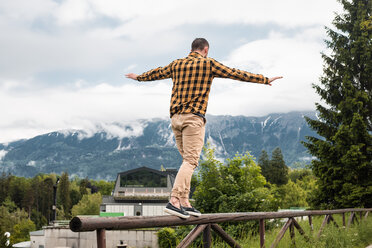 Mann balanciert auf einem Holzzaun in einem Bergdorf, Dolenci, Slowenien - CUF45990
