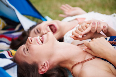 Friends lying on ground, laughing and enjoying music festival - CUF46013