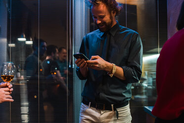 Mann benutzt Mobiltelefon auf Party in Wohnung - CUF46036