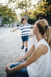 Mother sitting on bench, watching her son balancing - AZOF00071