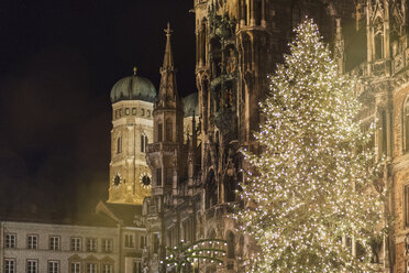 Germany, Munich, bright shining Christmas tree in front of old town hall and Cathedral of Our lady at night - MMAF00631