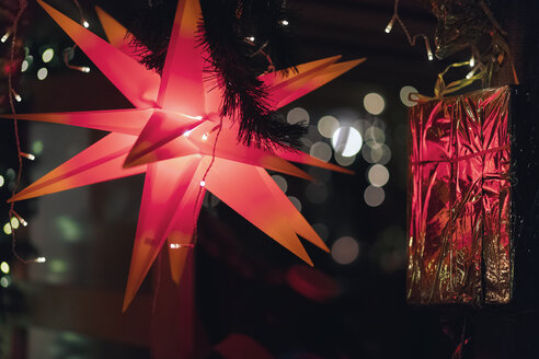Beleuchteter roter mährischer Stern und leuchtend rotes Weihnachtsgeschenk - MMAF00636