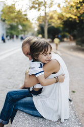 Mother sitting on bench, cuddling with her son - AZOF00074