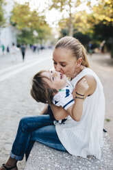 Mother sitting on bench, cuddling with her son - AZOF00075