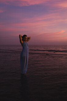 Junge Frau steht vor dem Meer bei Sonnenuntergang - MAUF01728