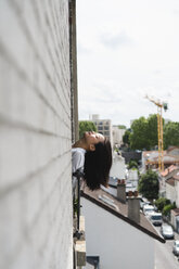 France, Paris, young woman leaning her head out of the window - AFVF01659