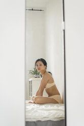 Young woman in underwear at home looking in mirror stock photo