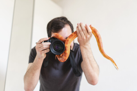 Schlange schlängelt sich um die Kamera eines Mannes, lizenzfreies Stockfoto