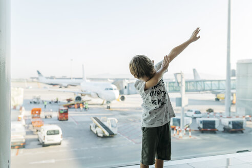Spanien, Flughafen Barcelona, Junge im Abflugbereich, tut so, als würde er fliegen - JRFF01907