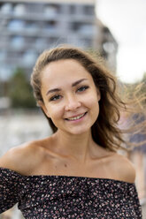 Porträt einer lächelnden schönen jungen Frau mit vom Wind zerzaustem Haar - AFVF01715