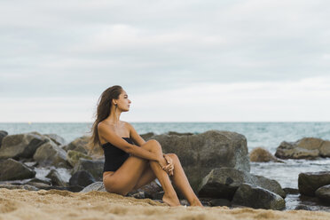 Schöne junge Frau im Badeanzug sitzt am Strand - AFVF01738