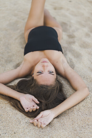 Porträt einer schönen jungen Frau im Sand liegend, lizenzfreies Stockfoto