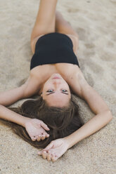 Porträt einer schönen jungen Frau im Sand liegend - AFVF01746