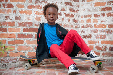 Porträt eines Jungen auf einem Skateboard sitzend - ISF19669