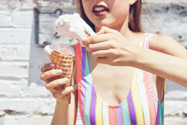 Young woman holding two melting ice cream cones, cropped - ISF19680