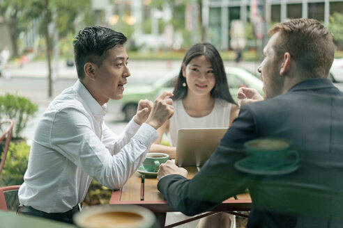 Group of businesspeople, having meeting at cafe, using laptop, outdoors - ISF19722