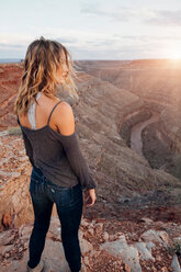 Young woman in remote setting, standing on cliff edge, looking at view, rear view, Mexican Hat, Utah, USA - ISF19736
