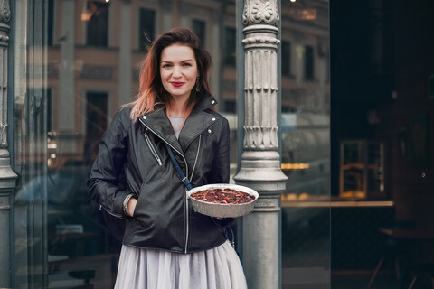 Porträt einer Frau auf der Straße, die einen Teller mit Essen hält, lizenzfreies Stockfoto