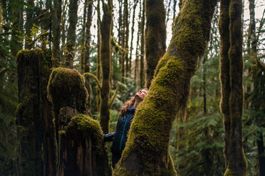 Frau schaut auf einen moosbewachsenen Baum im Wald, Squamish, Kanada - ISF19767