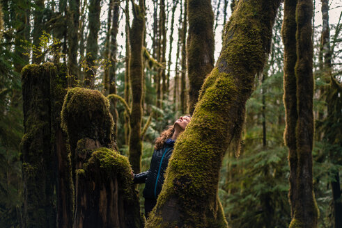 Frau schaut auf einen moosbewachsenen Baum im Wald, Squamish, Kanada - ISF19767