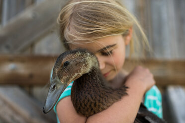 Girl with eyes closed hugging farm duck - ISF19824