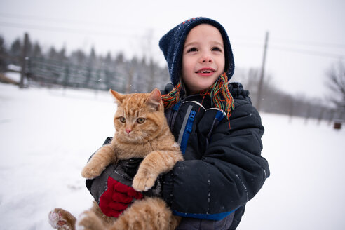 Junge trägt Katze im Schnee - ISF19825