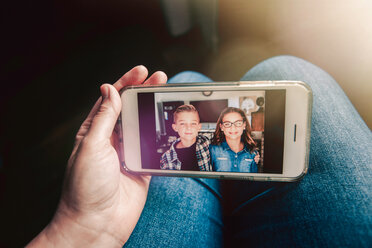 Mother holding smartphone with picture message of twin girl and boy, personal perspective - ISF19859