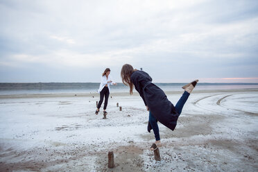 Women balancing on wooden stumps on beach, Odessa, Ukraine - ISF19893