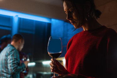 Woman drinking wine at party in apartment - ISF19909