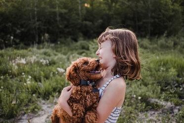 Girl laughing at puppy's kisses - ISF19912