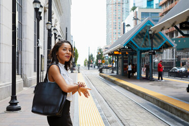 Businesswoman checking time by light rail line - ISF19934