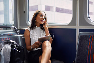 Businesswoman using digital tablet on train - ISF19952