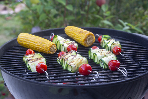 Gegrillte vegetarische Grillspieße, Tomaten-, Schafskäse- und Zucchinischeiben, Maiskolben auf dem Grill, lizenzfreies Stockfoto