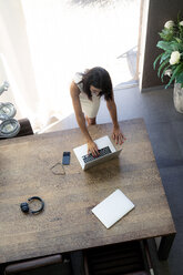 Blick von oben auf eine Frau, die einen Laptop am Schreibtisch benutzt - HHLMF00531