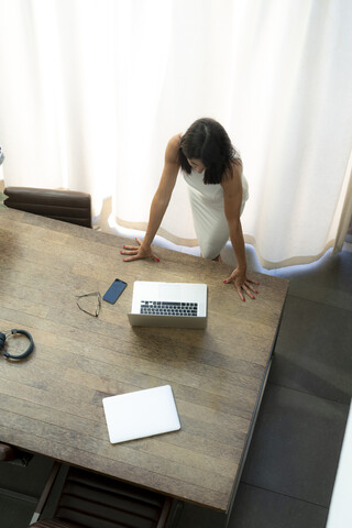Blick von oben auf eine Frau, die einen Laptop am Schreibtisch benutzt, lizenzfreies Stockfoto