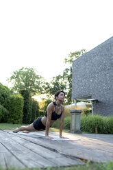 Frau übt Yoga im Garten - HHLMF00548