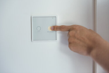 Frau benutzt Smart-Home-Schalter an der Wand - DIGF05121