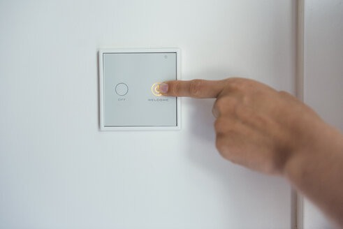 Woman using smart home switch on wall - DIGF05121