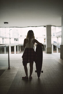 Junge Frau mit ihrem Longboard in einer Wohngegend - RAEF02147