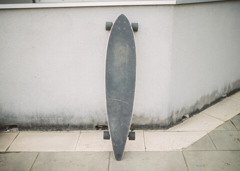 Longboard auf der Straße gegen eine Wand gelehnt, lizenzfreies Stockfoto