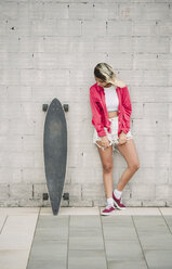 Portrait of a young woman with her long board, in front of a wall - RAEF02166