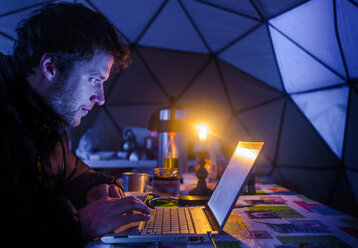 Mann auf Expedition, benutzt Laptop im Lager, Fletanes Lager, Narsaq, Kitaa, Grönland - CUF46055