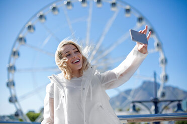 Woman taking selfie in front of Cape Wheel, Victoria and Alfred Waterfront, Cape Town, South Africa - CUF46063