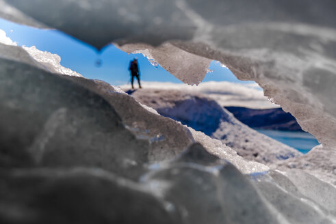 Peek through hole in ice at tourist in distance, Narsaq, Vestgronland, Greenland - CUF46073