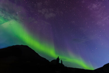 Tourists looking up at Aurora Borealis, Narsaq, Vestgronland, Greenland - CUF46074