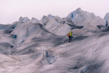 Männlicher Wanderer wandert über graue, schneebedeckte Landschaft, Narsaq, Vestgronland, Südgrönland - CUF46096