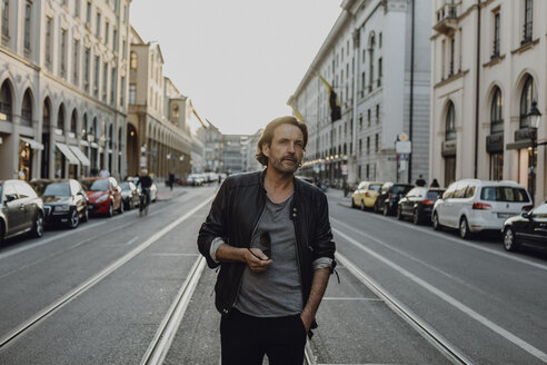 Man wearing leather jacket walking in the street, Munich, Germany - JLOF00231