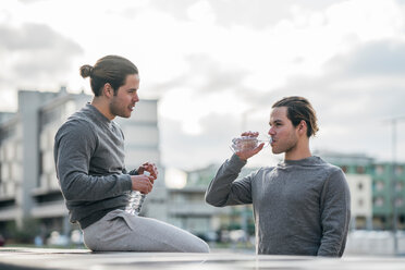Junge erwachsene männliche Zwillinge machen eine Trainingspause und trinken Wasser - CUF46168