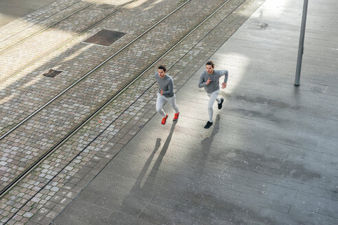 Junge erwachsene männliche Zwillinge, die zusammen auf dem Bürgersteig laufen, Blickwinkel - CUF46171