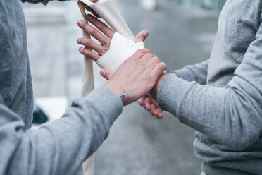 Male adult twin boxers training outdoors, bandaging hands with hand wraps, cropped - CUF46176